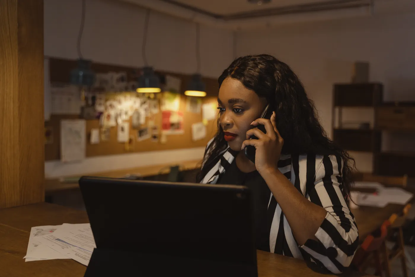 Business owner on a phone call at her desk in the evening.