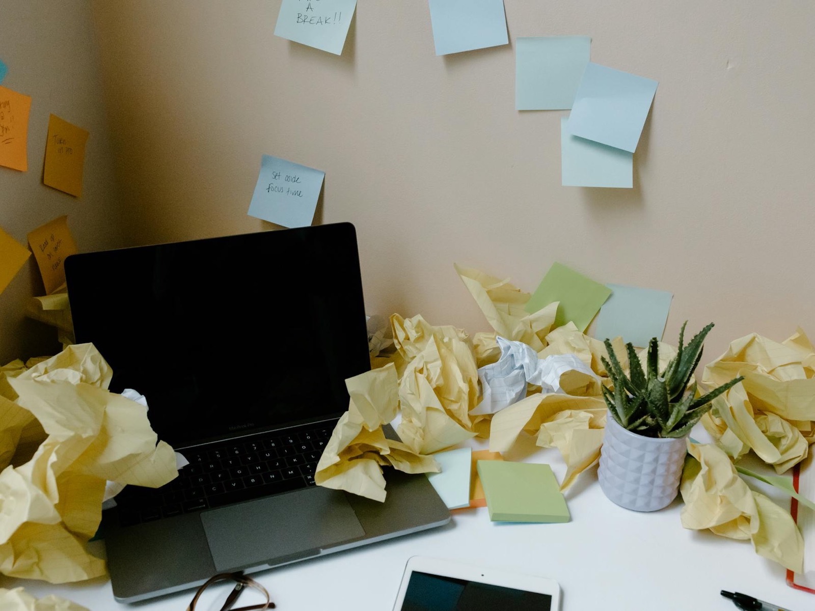 A laptop buried in sticky notes and crumpled paperwork before an operations cleanup