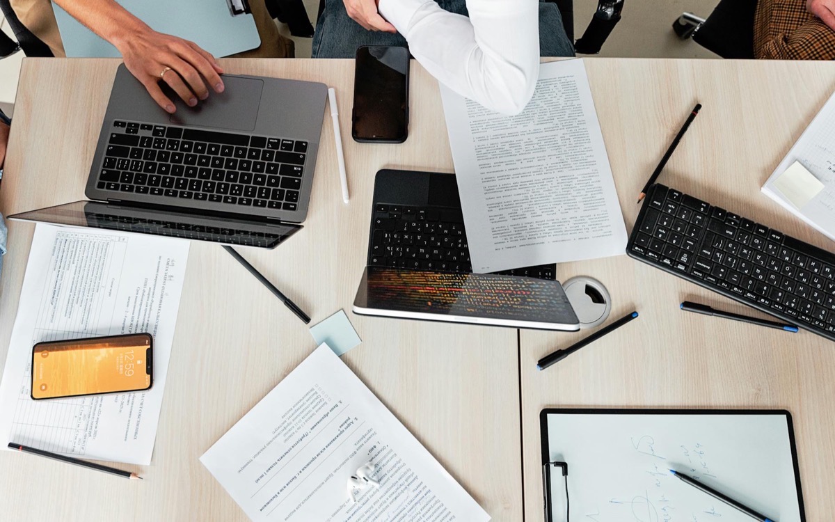 Documents, laptops, and planning notes spread across an operations audit table